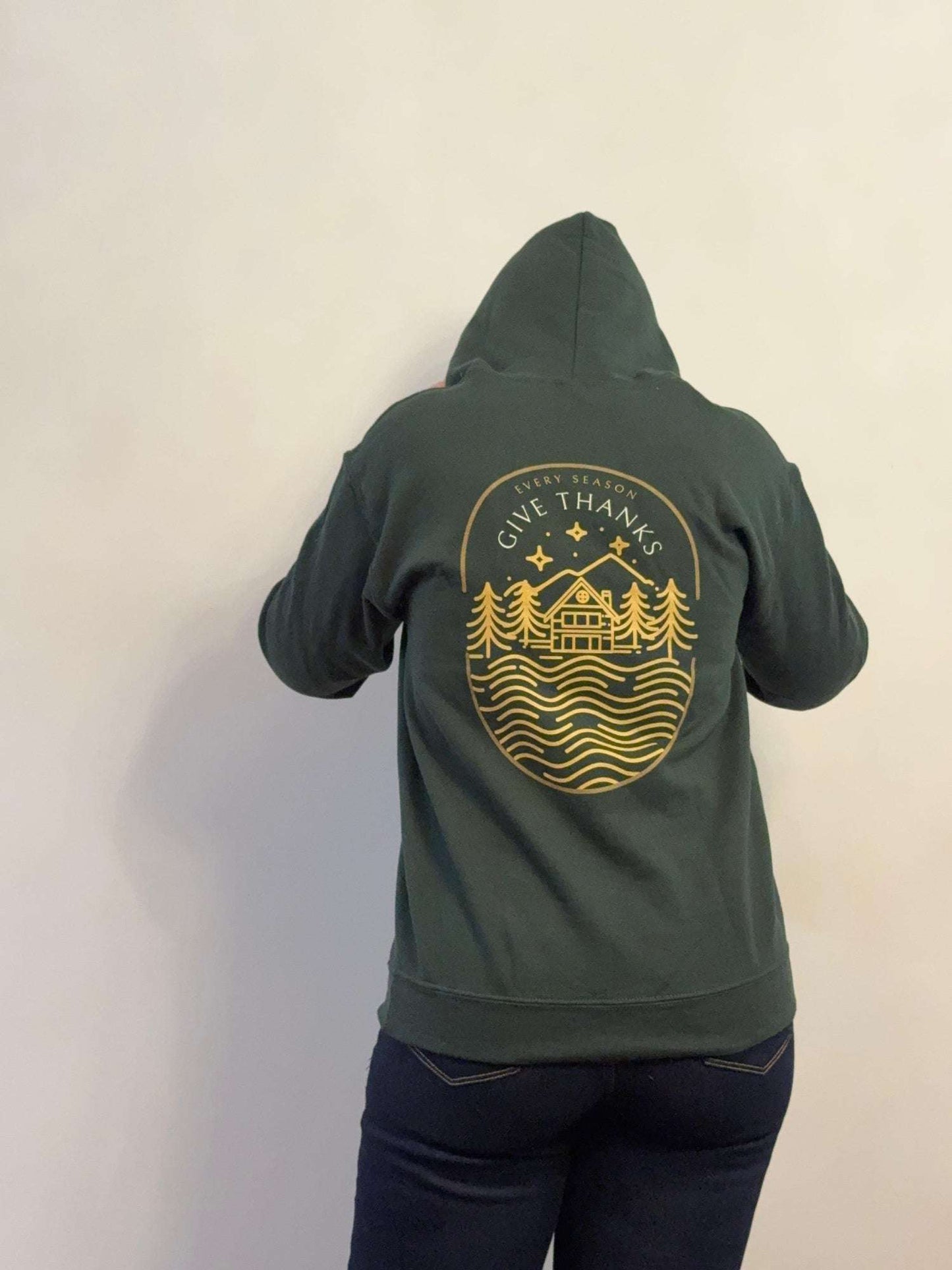 Green hoodie with a gold graphic on the back against a plain background