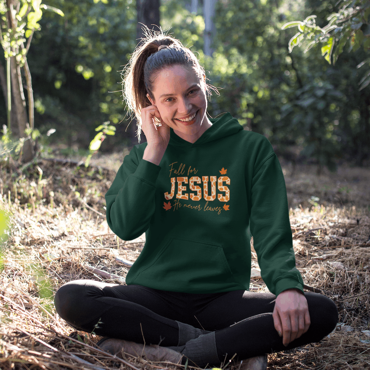 Person wearing a green hoodie with 'Fall for Jesus' text, sitting in a natural setting.