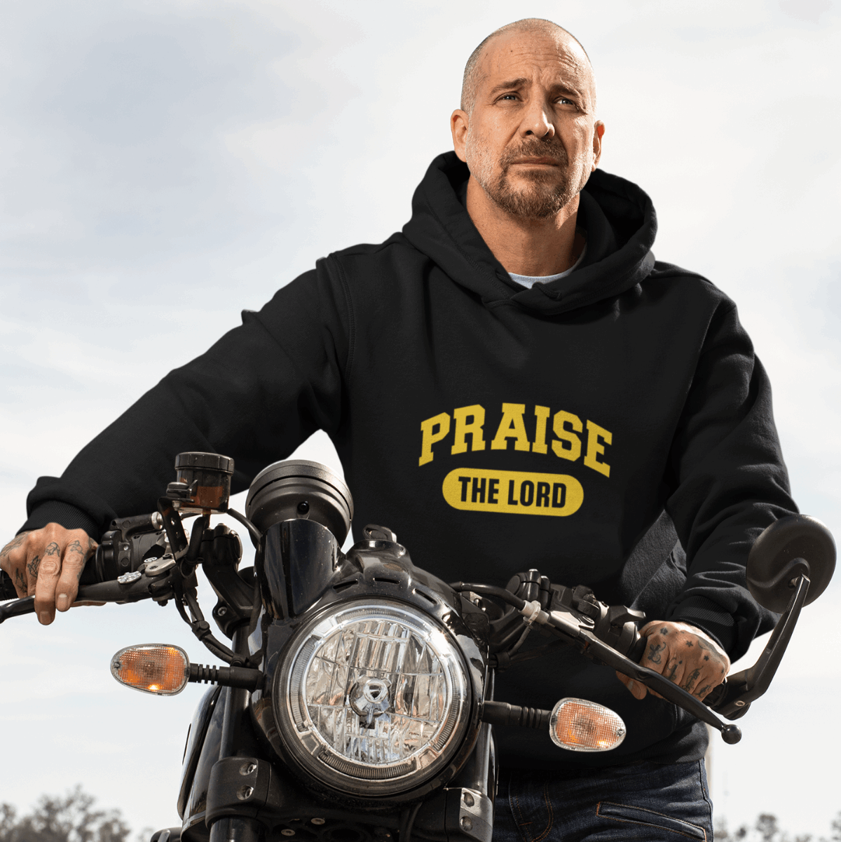 Person wearing a black hoodie with 'PRAISE THE LORD' text on a motorcycle.