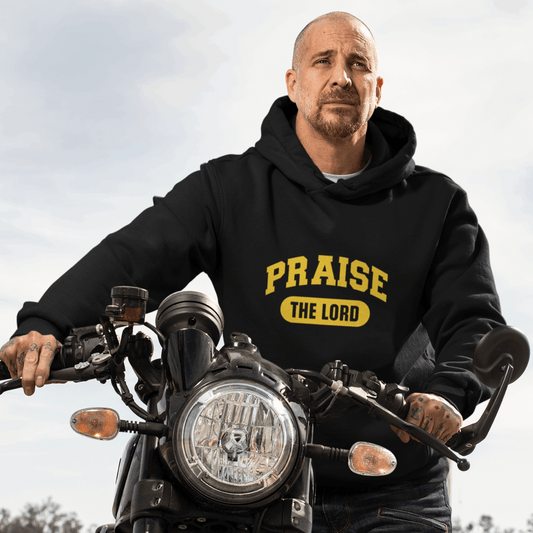 Person wearing a black hoodie with 'PRAISE THE LORD' text on a motorcycle.