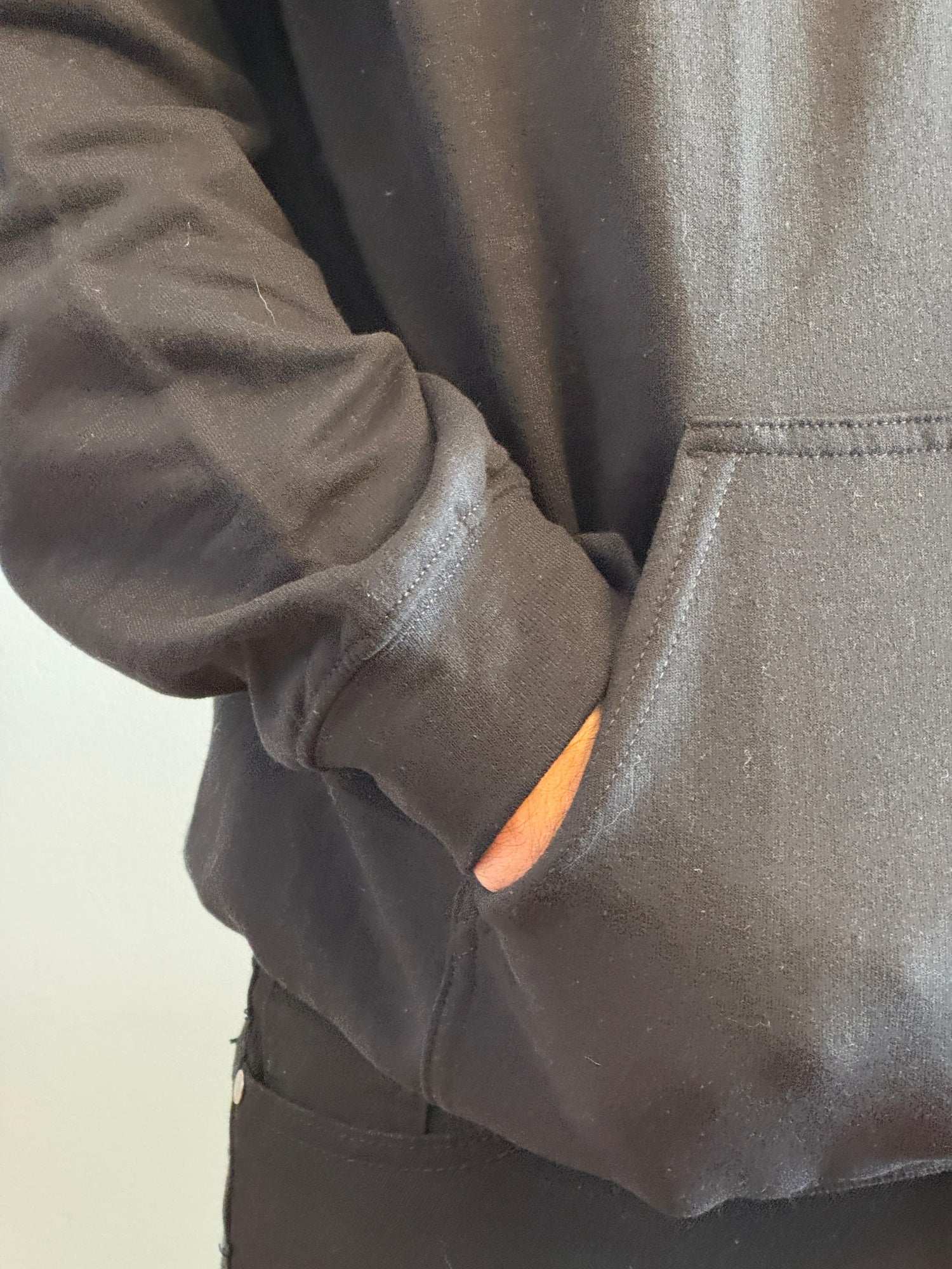 Close-up of a person wearing a dark gray jacket with a pocket.